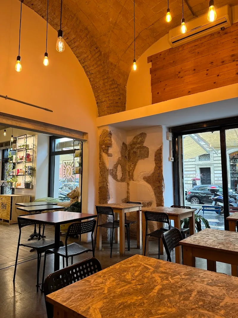 warm-lit café interior with hanging bulbs, brick arch, and street-facing windows., sansone coffee artisan microroastery & spe