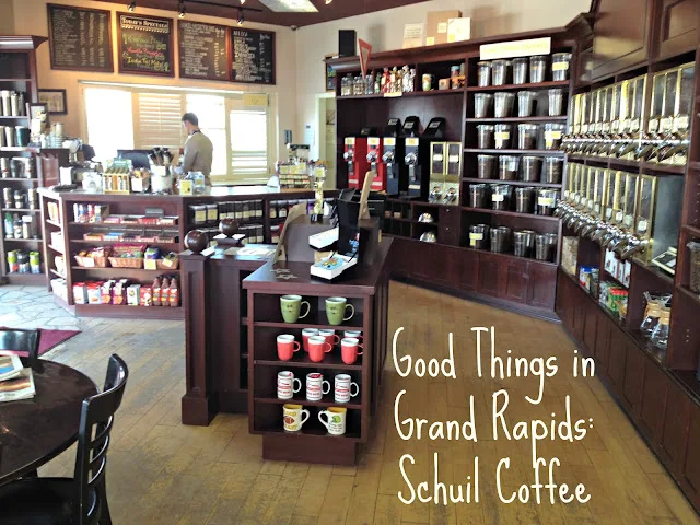 spacious coffee shop interior with dark wood shelving, merchandise displays, and counter service area., schuil coffee company
