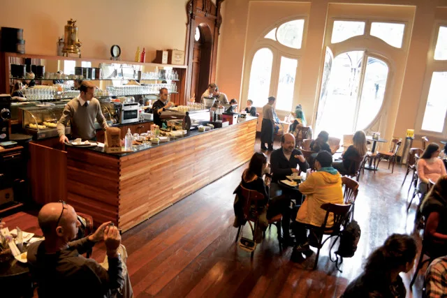 busy café interior with counter service, wooden floors, and seated customers enjoying beverages., senac café-escola paço da l