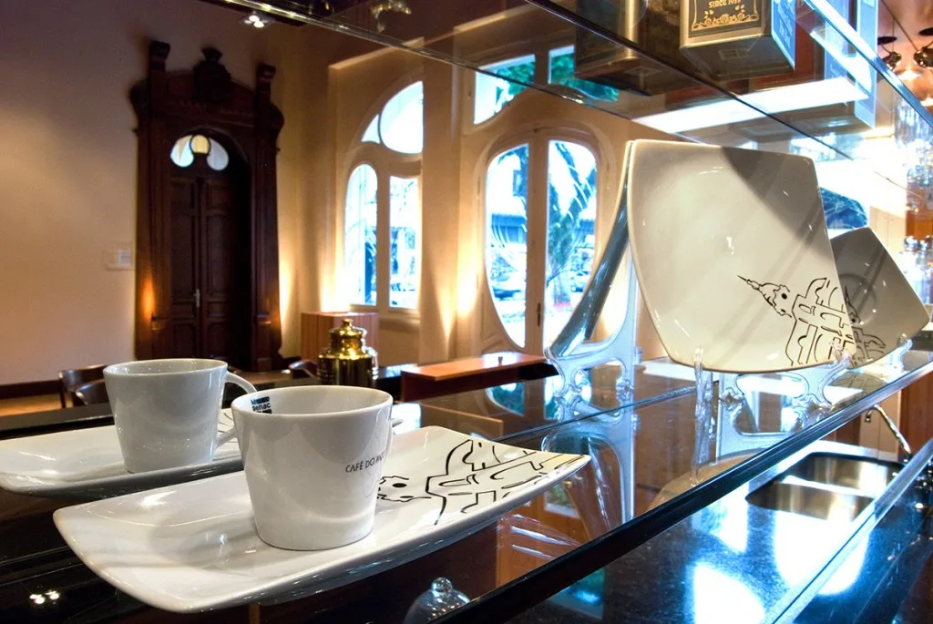 elegant café interior with white cups, artistic tableware, and decorative wooden door display., senac café-escola paço da lib