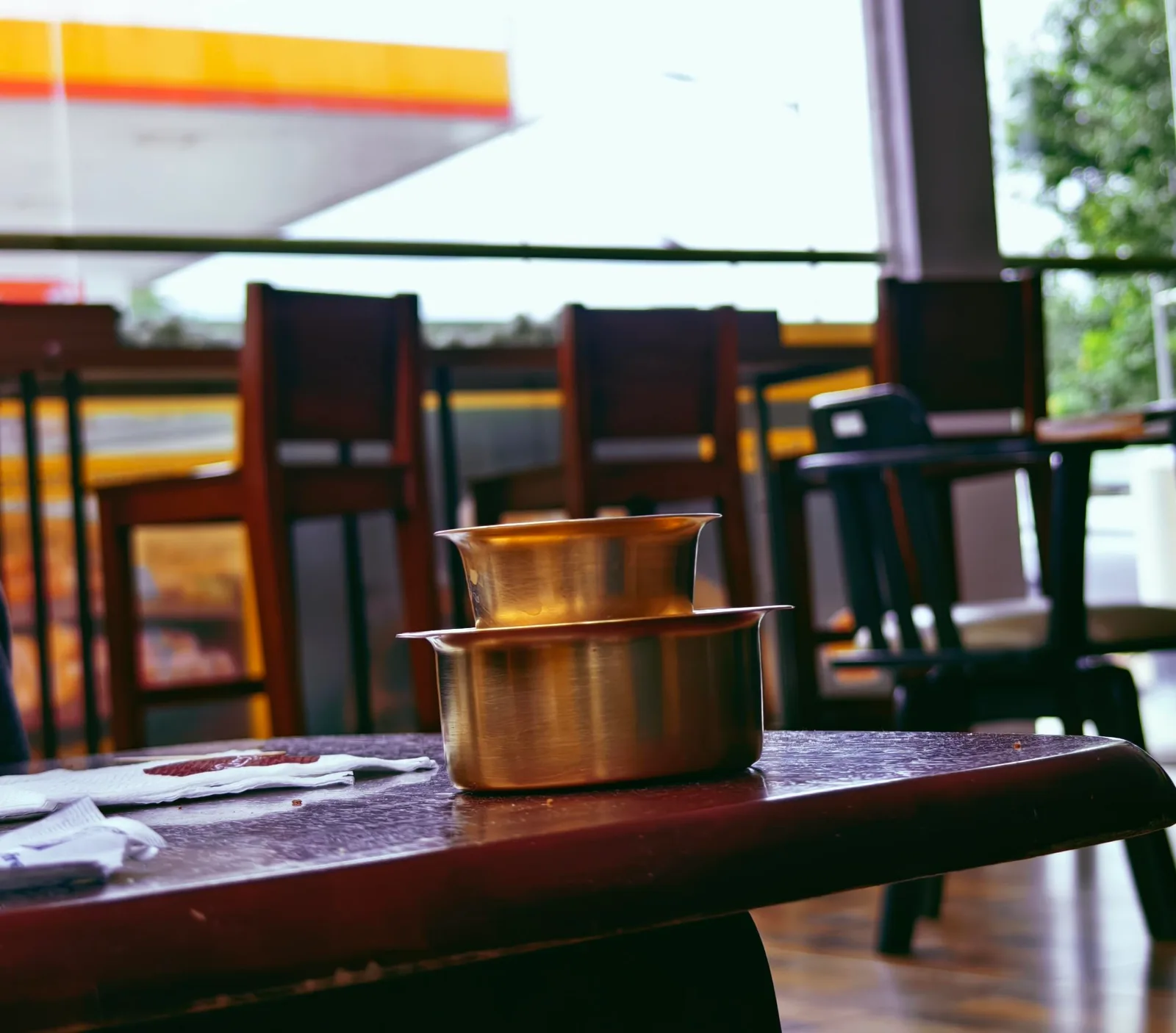 golden brass bowls on wooden table at outdoor restaurant terrace., shell, chennai