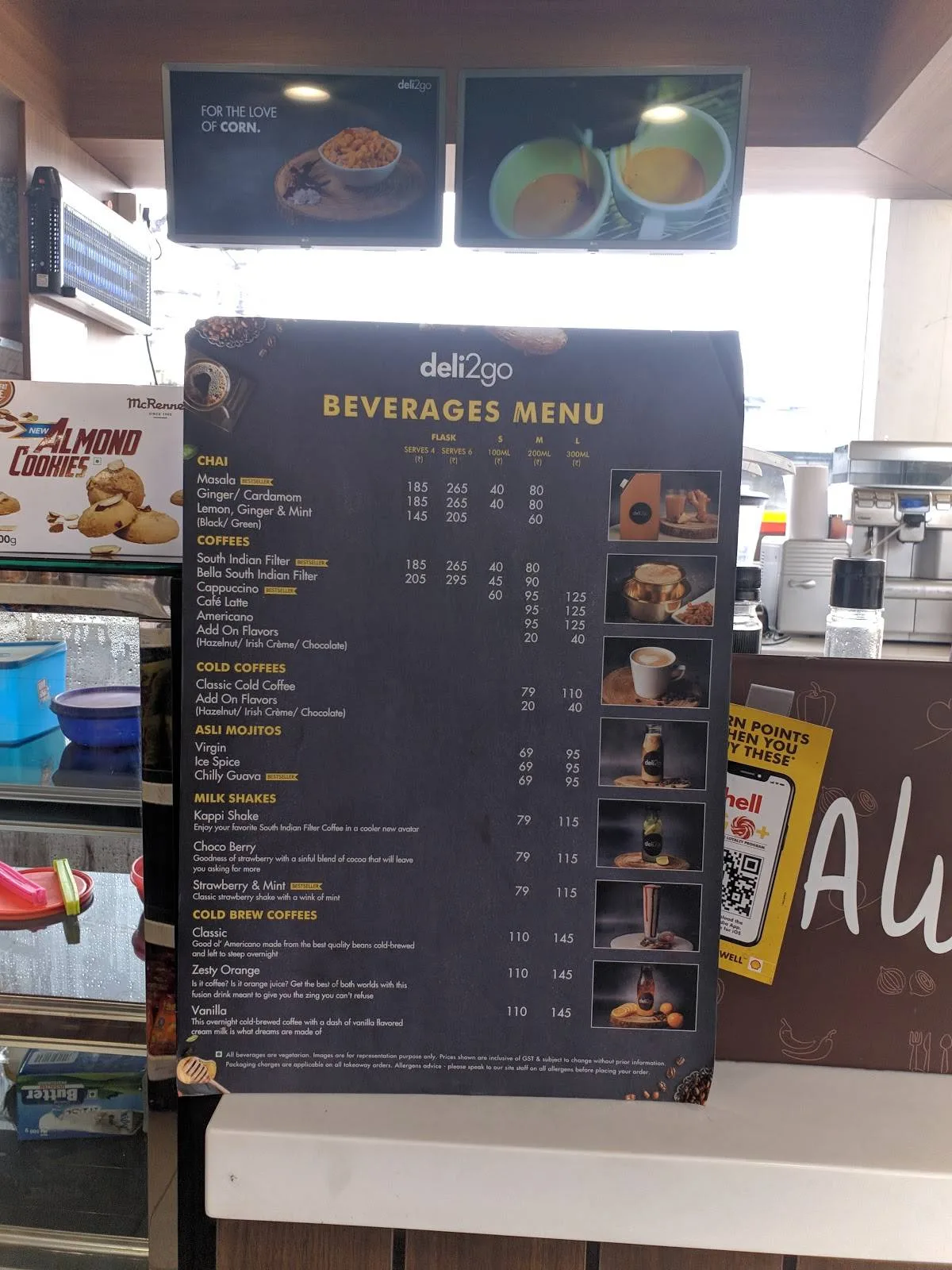 deli2go beverages menu board displaying chai, coffees, cold drinks, and milk shakes with prices., shell, chennai