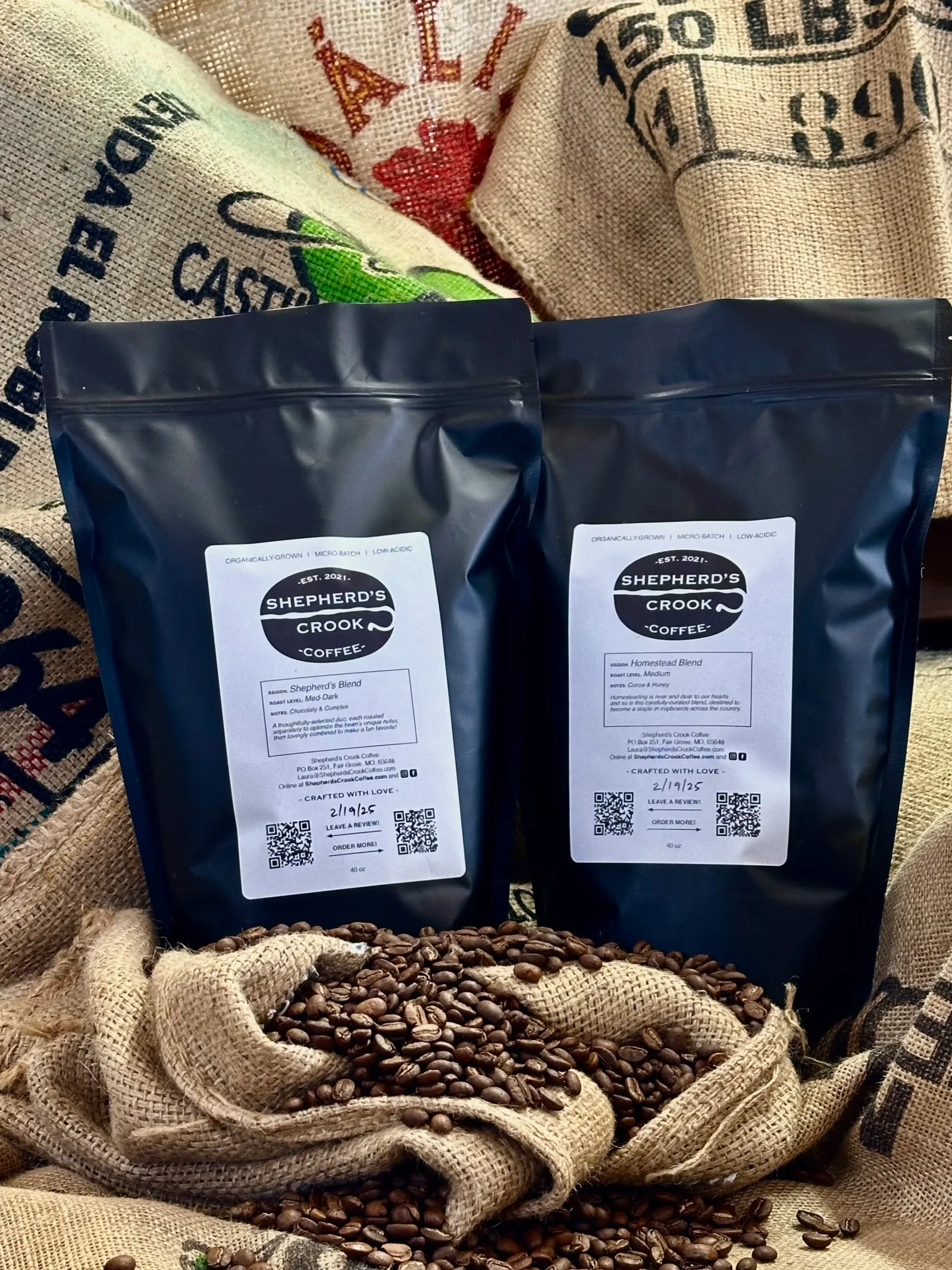 two dark blue shepherd's crook coffee bags with labels displayed on burlap with scattered beans., shepherd’s crook coffee, sp