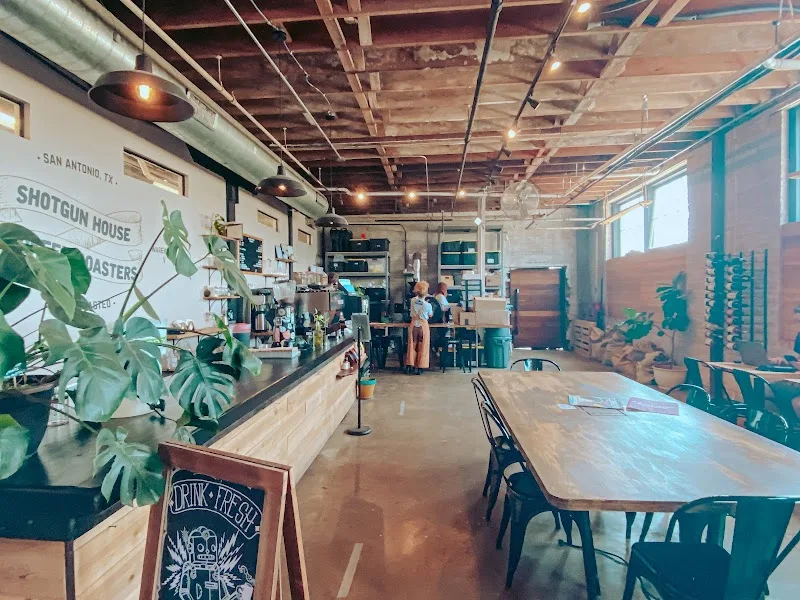modern café interior with counter, wooden tables, plants, and exposed ceiling beams., shotgun house coffee roasters, san anto