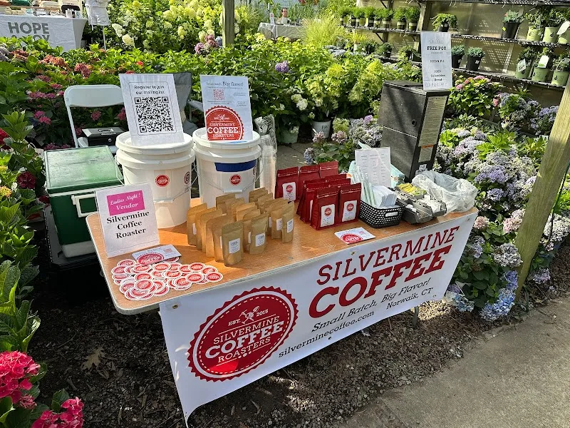 silvermine coffee vendor booth with dispensers, packaged goods, and flowering plants backdrop., silvermine coffee roasters, n
