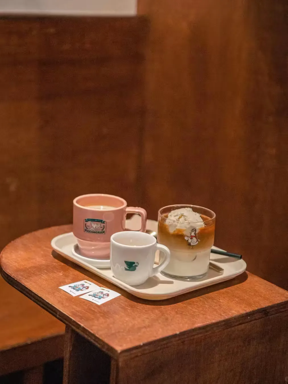 wooden table with pink mug, white mug, and iced drink on ceramic tray., sim coffee house, seoul
