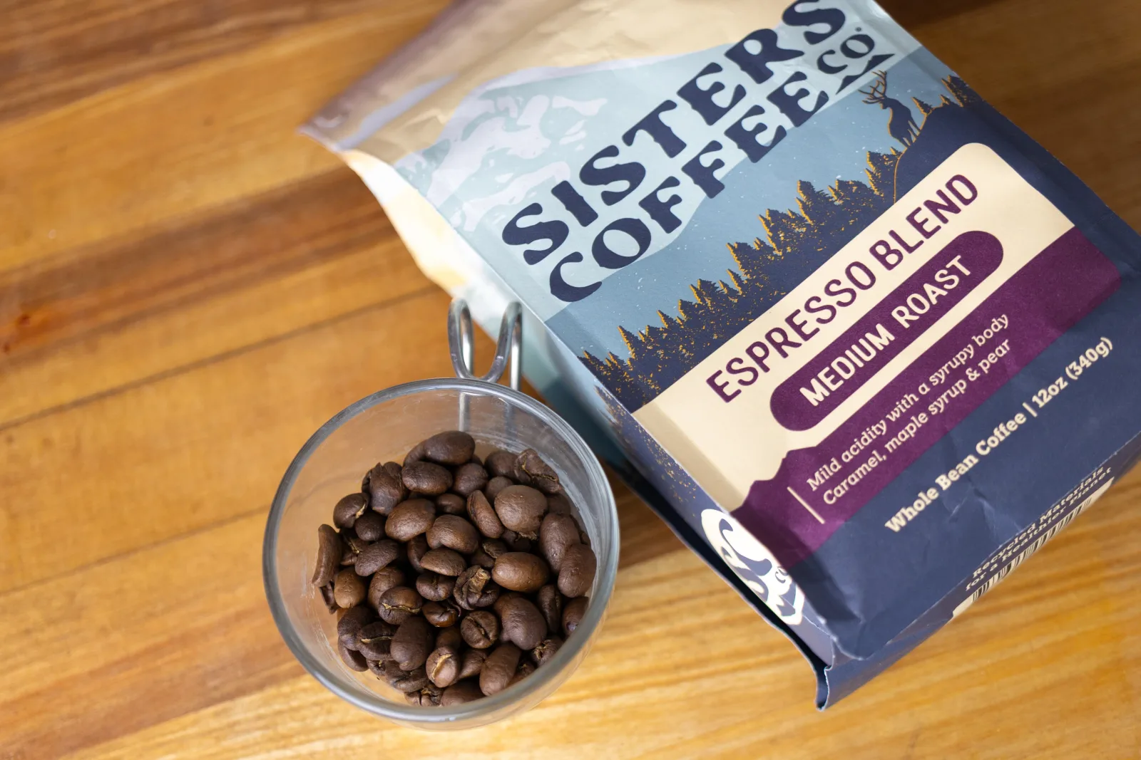 sisters coffee espresso blend bag with whole beans in glass bowl on wooden surface., sisters coffee company, sisters