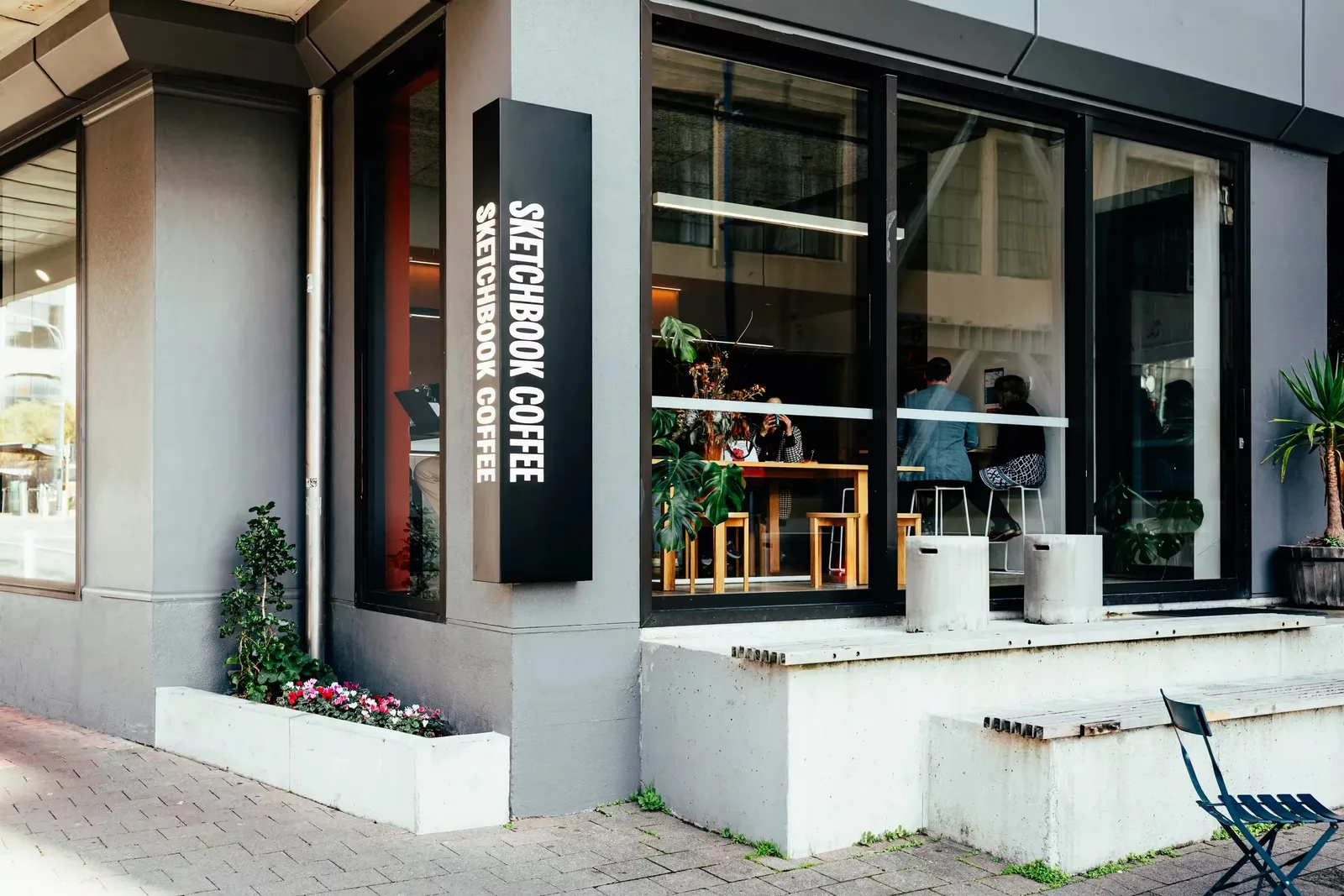 modern sketchbook coffee storefront with black signage and potted plants outside., sketchbook coffee, wellington