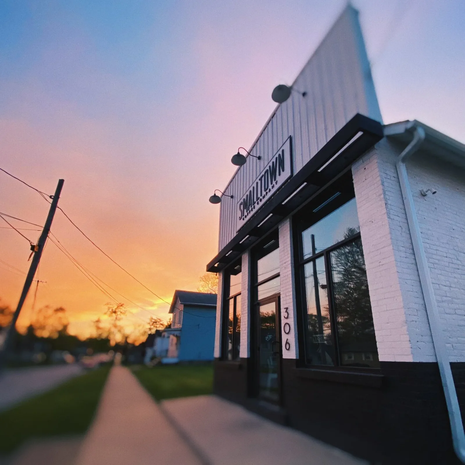 modern white building with peaked roof at sunset, address number 306 visible., smalltown coffee co., crown point