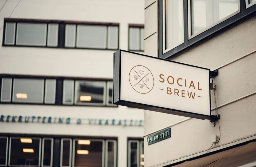 social brew café sign on modern building exterior with street name visible below., social brew, copenhagen