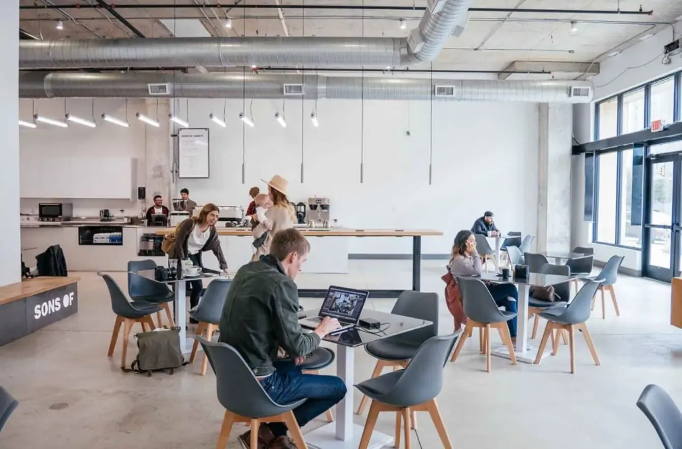 modern office space with people working at tables and kitchen area visible., sons coffee, fort worth