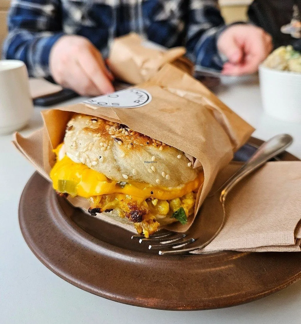 sesame seed bagel sandwich with melted cheese and egg on brown plate., sörkan rinkula, helsinki