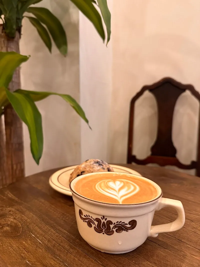 latte with heart latte art, pastry, plant, and wooden chair indoors., sote coffee roasters, new york city