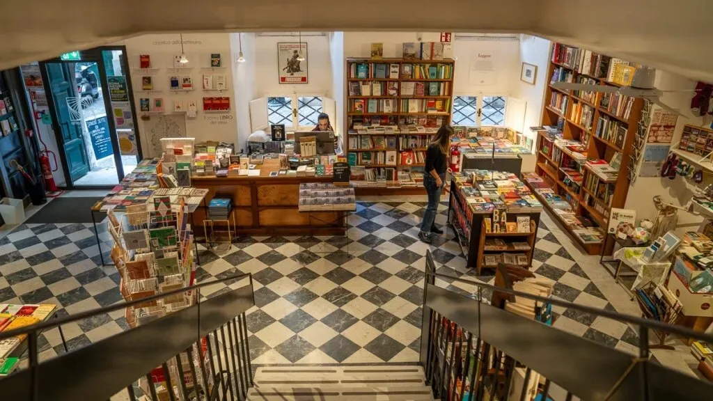 bookstore interior with checkered floor, wooden shelves, and browsing customers., spazio sette libreria, rome