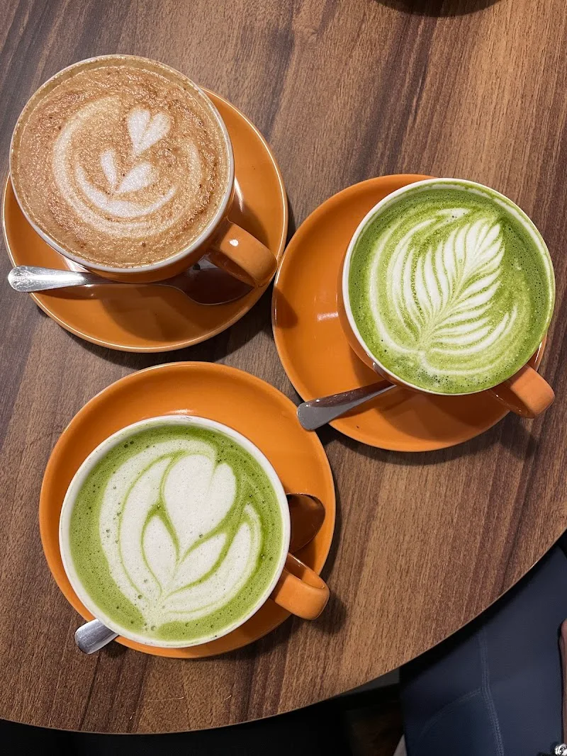 three specialty coffees with latte art on wooden table in orange cups., specialty coffee mayan ☕🥐, valència