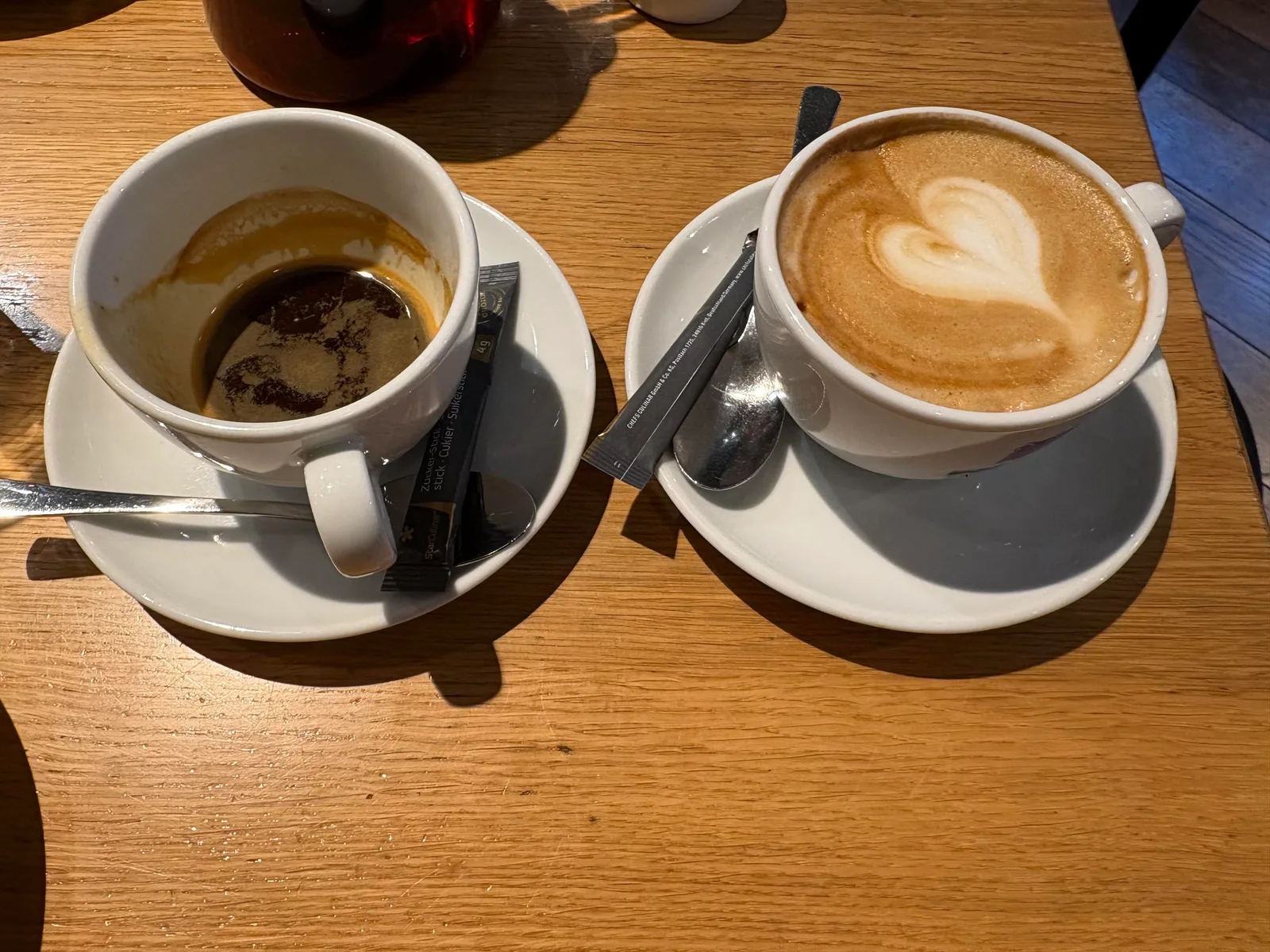 two coffee cups on wooden table, one espresso and one cappuccino with latte art., speicherstadt coffee roastery, hamburg