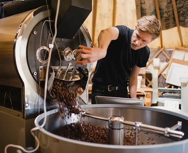 man operating coffee roaster, pouring roasted beans into metal cooling drum., split bean roasting co., lebanon