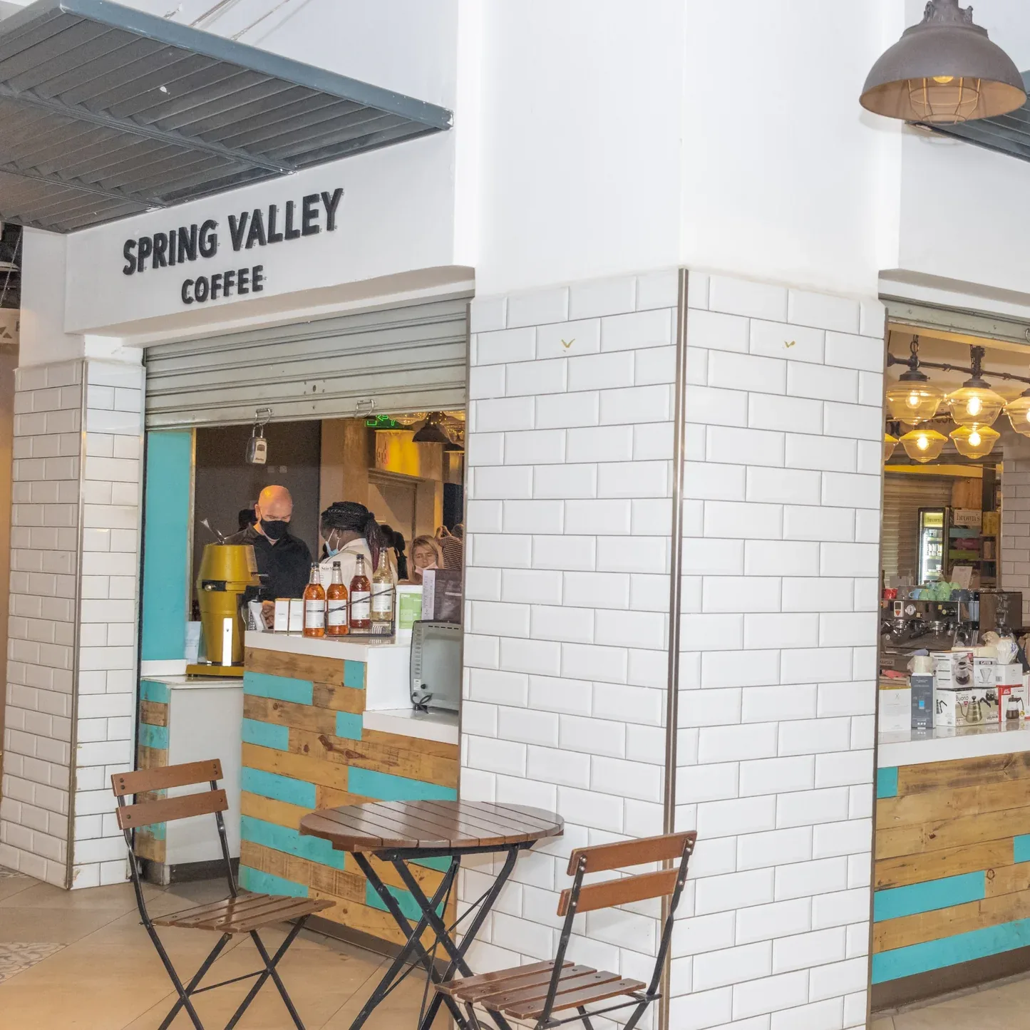 spring valley coffee kiosk with white subway tile, turquoise wood accents, and seating area., spring valley coffee @ spring v