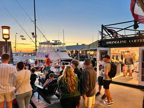 waterfront marketplace at dusk with boats, shops, and gathered crowds., springline coffee, newport