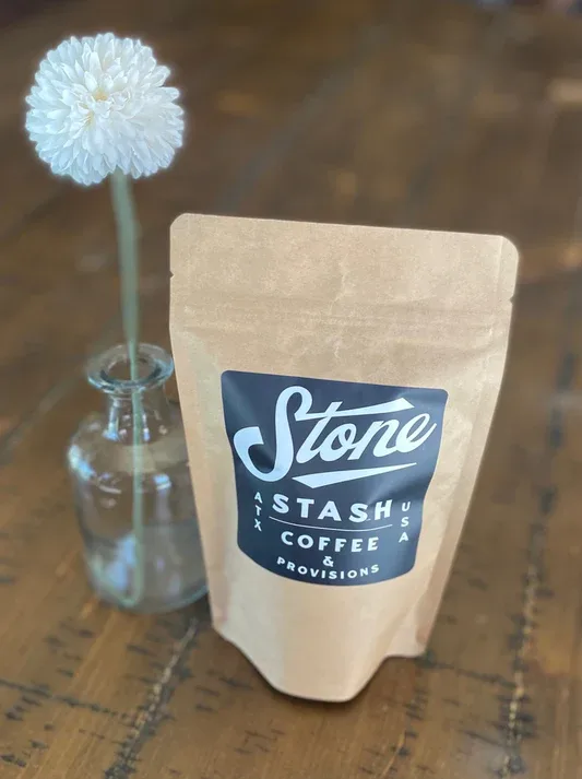 stone stash coffee bag next to white flower in glass vase., stone stash coffee, austin