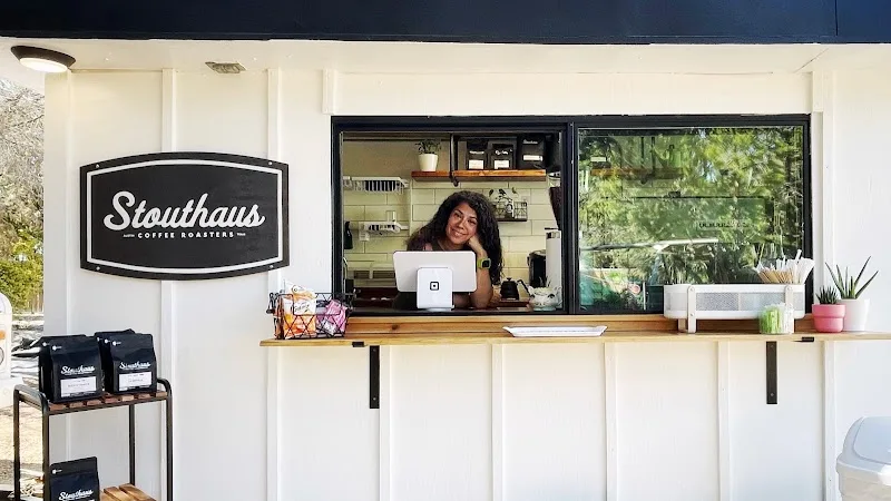 stouthaus coffee shop counter with barista, wooden service window, and potted plants., stouthaus coffee roasters, austin