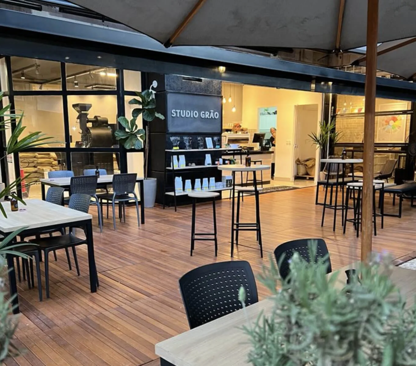 modern studio space with dark chairs, wooden floors, and potted plants., studio grão coffee roasters, brasília