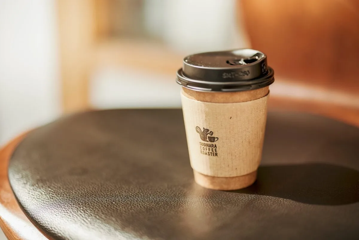 coffee cup with black lid on dark table in bright interior space., sugihara coffee roaster, osaka