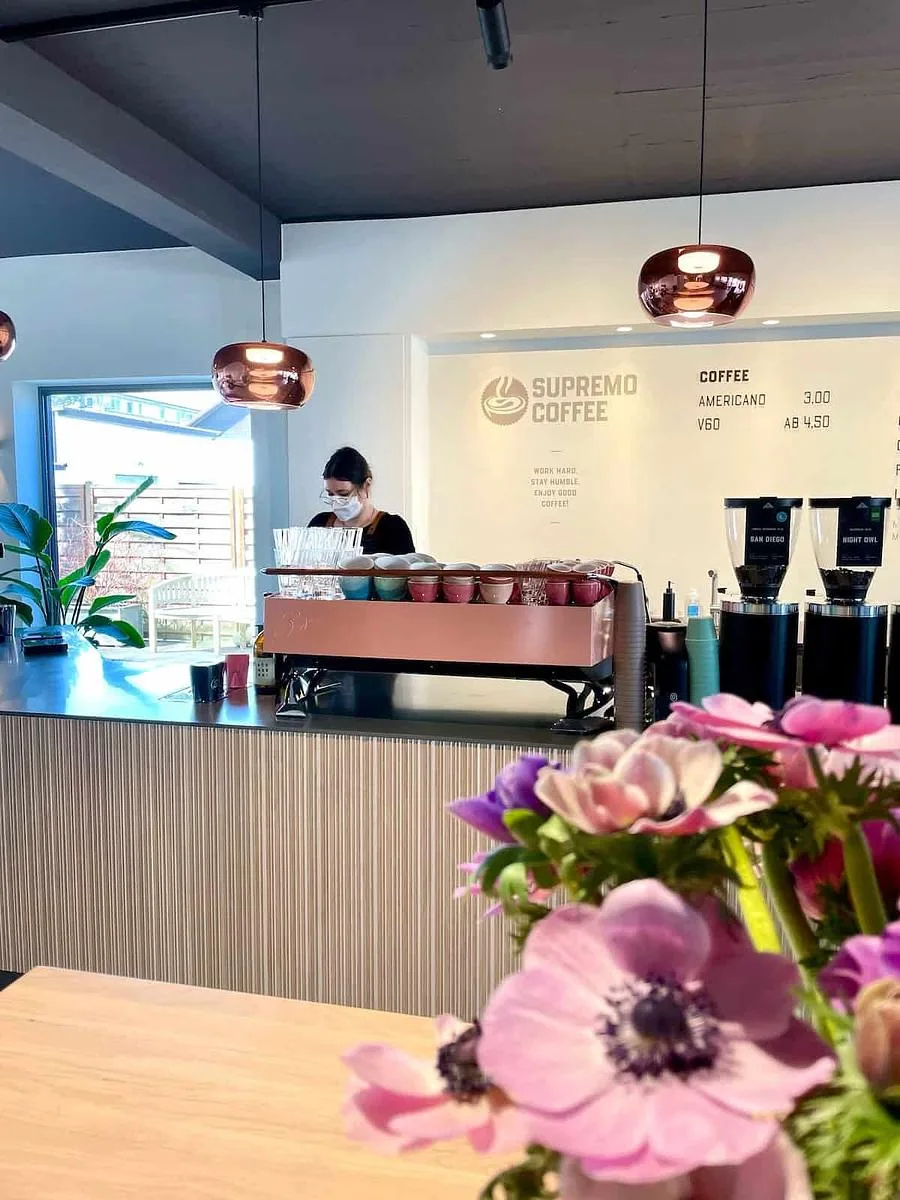 modern coffee shop interior with barista, copper pendant lights, and pink flowers., supremo, unterhaching