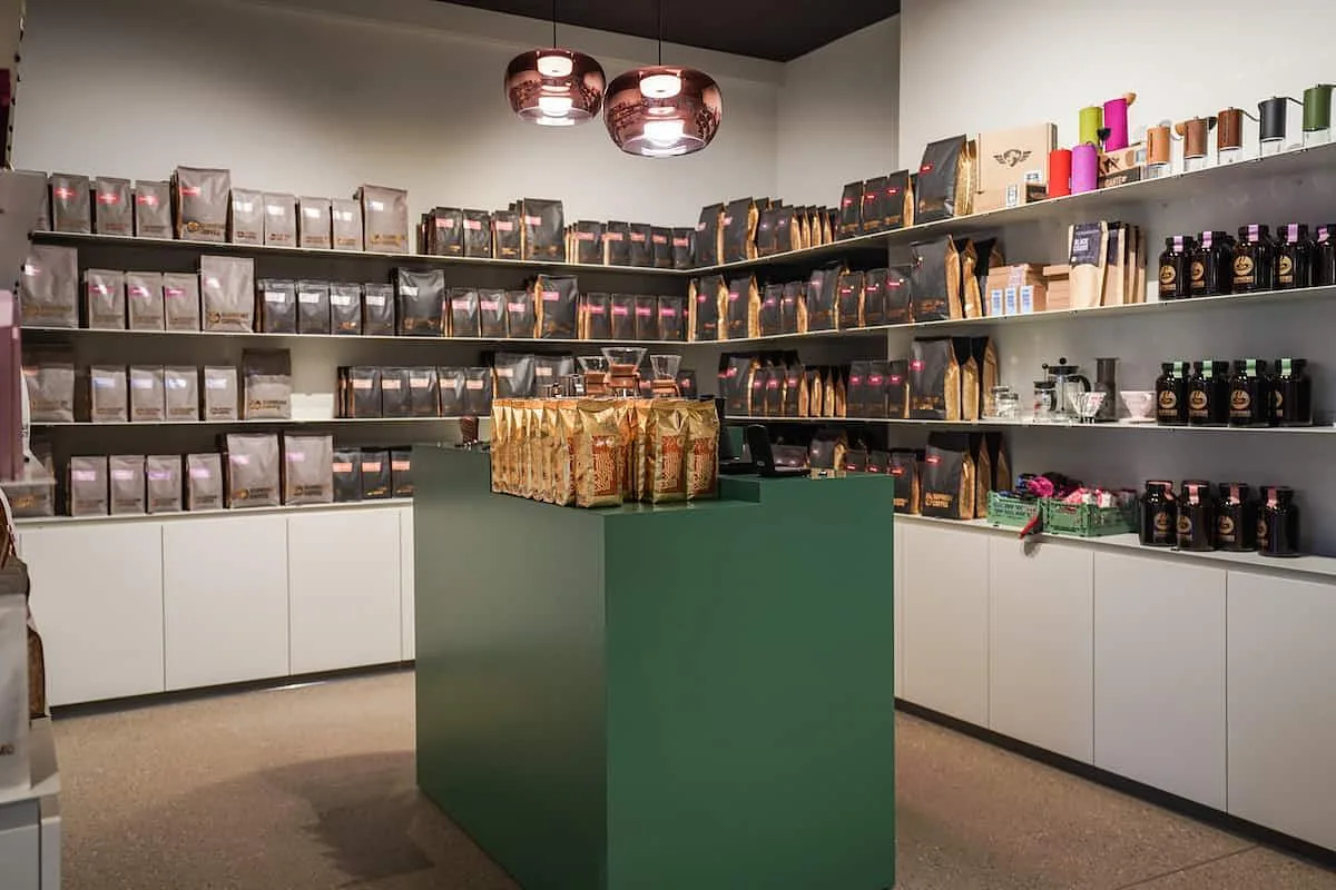 coffee shop interior with shelves displaying packaged beans and products, green counter., supremo, unterhaching