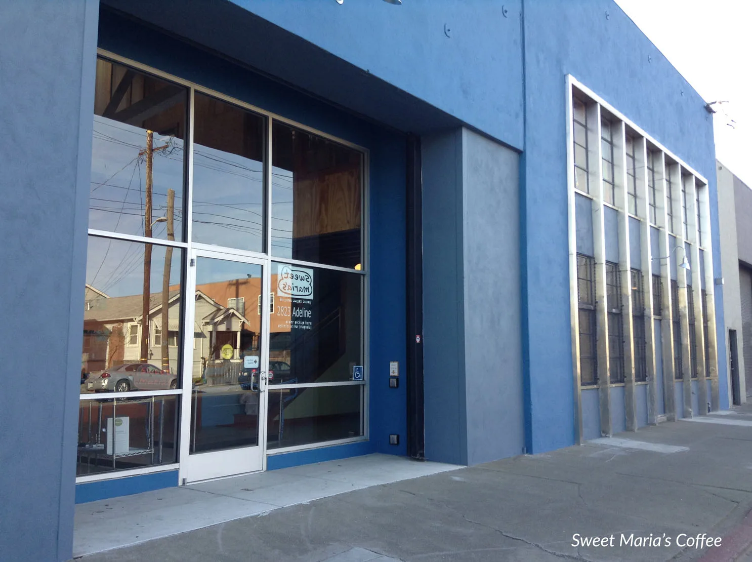 blue storefront with large windows and white door frame on street., sweet maria's coffee warehouse, oakland