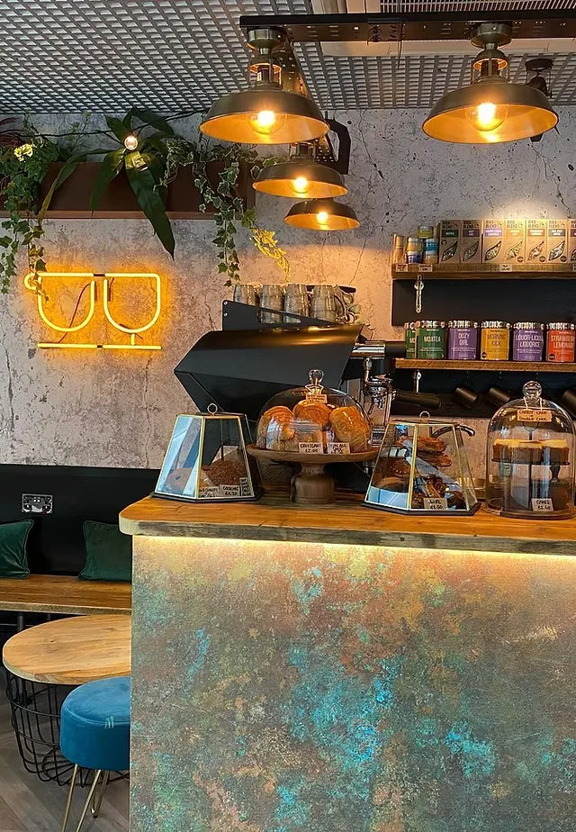 modern café interior with industrial pendant lights and neon signage above counter., t4 liverpool street, london