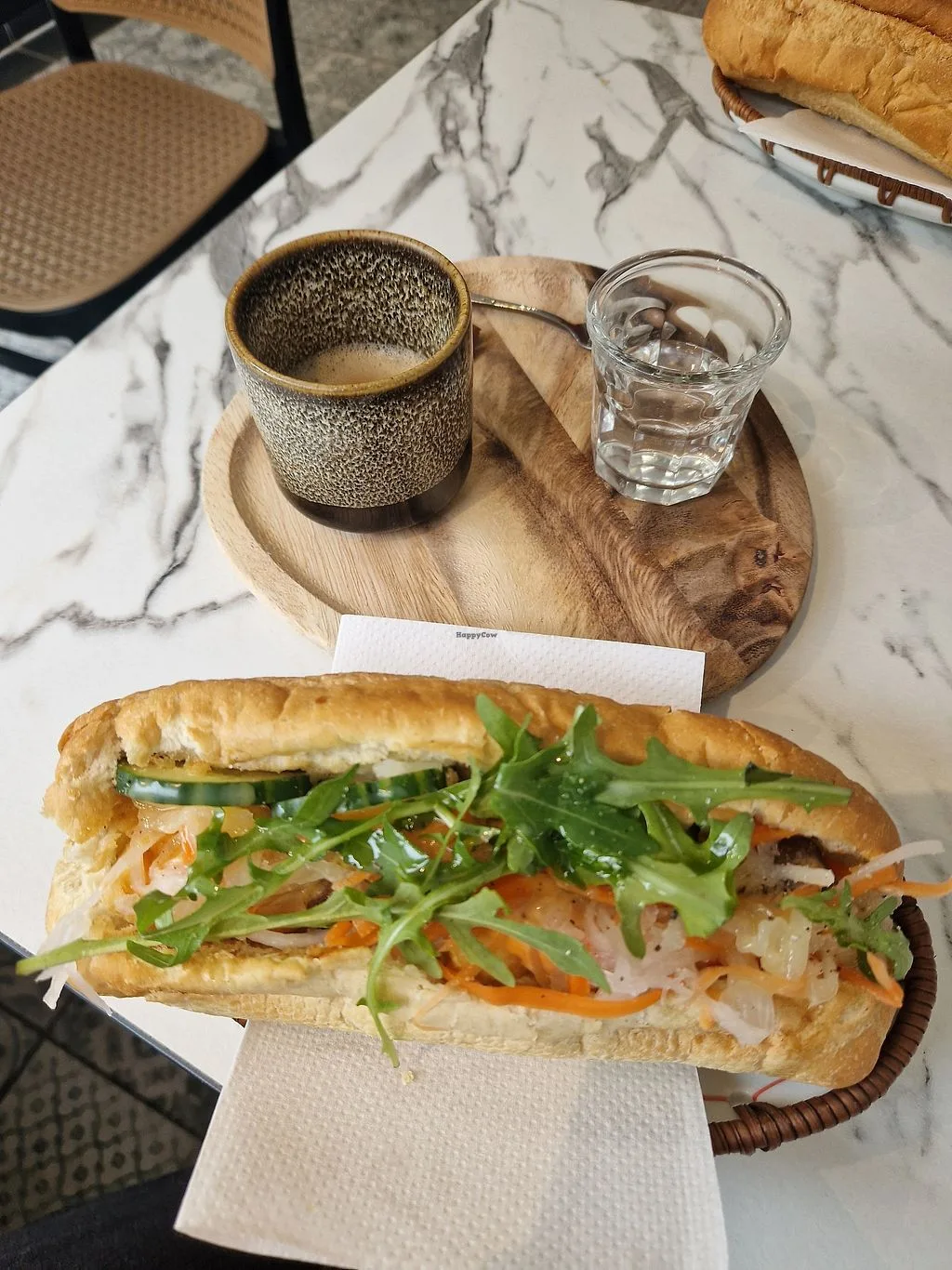 banh mi sandwich with textured ceramic mug and water glass on marble table., the annamites coffee roasters, munich