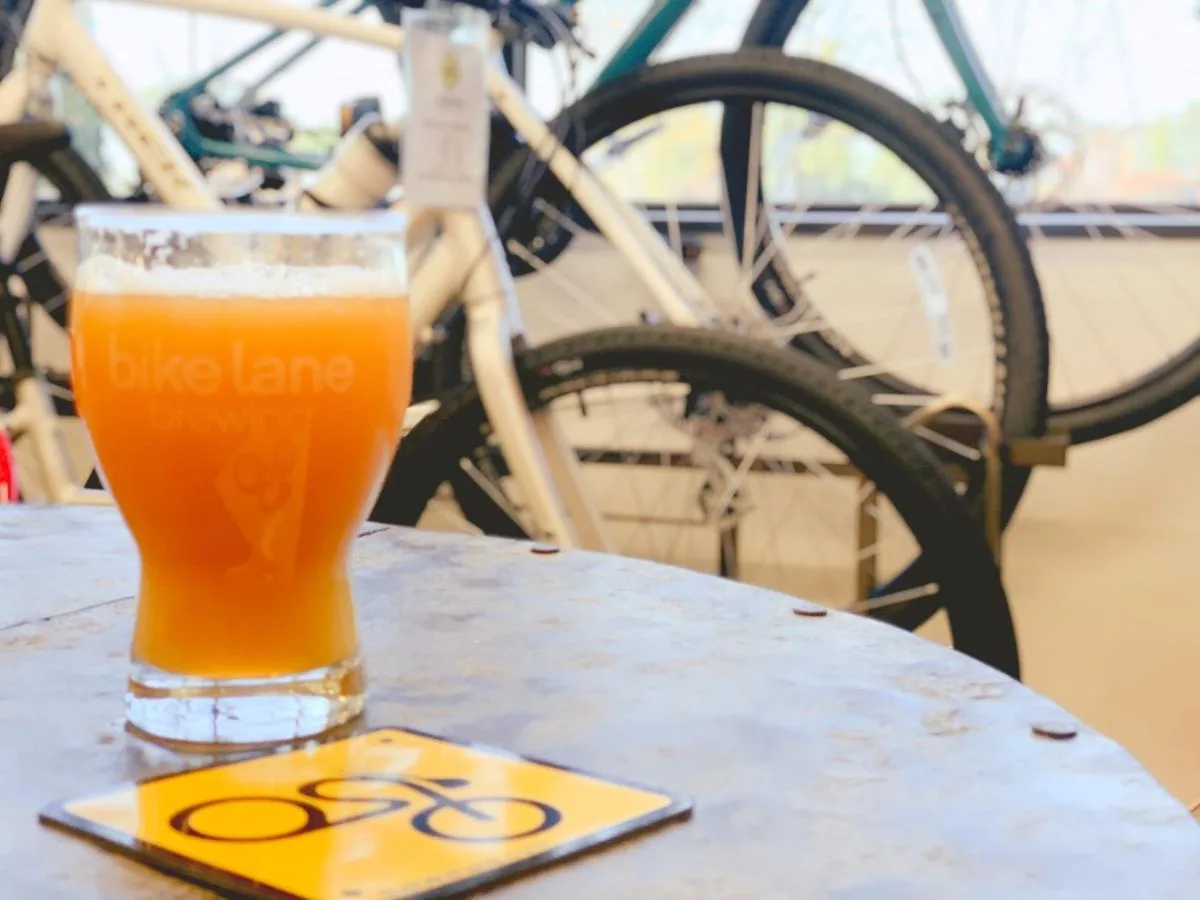 glass of orange beer beside bicycle with yellow coaster on table., the bike lane bicycle shop and brewery, washington