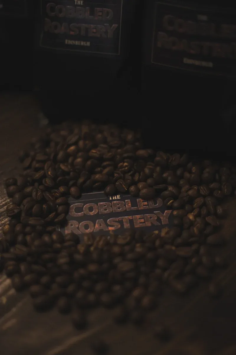 coffee beans scattered around "the cobbled roastery" branded metal plaque., the cobbled roastery, edinburgh