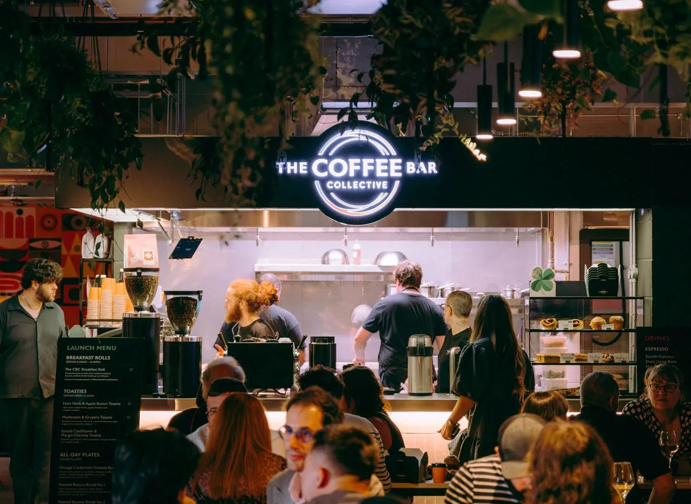 neon-lit coffee bar counter with staff serving customers in bustling café setting., the coffee bar birmingham, birmingham