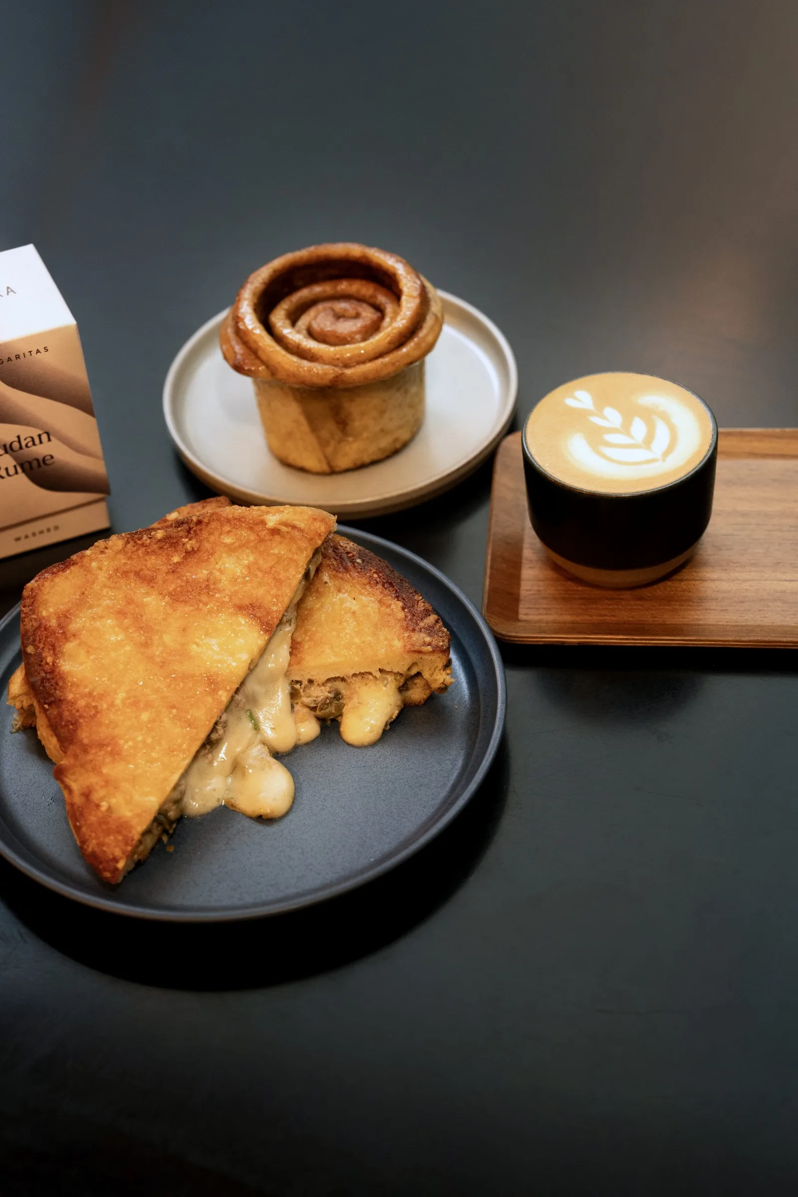 pastry spread with cheese sandwich, cinnamon roll, and latte with latte art., the coffee bar birmingham, birmingham