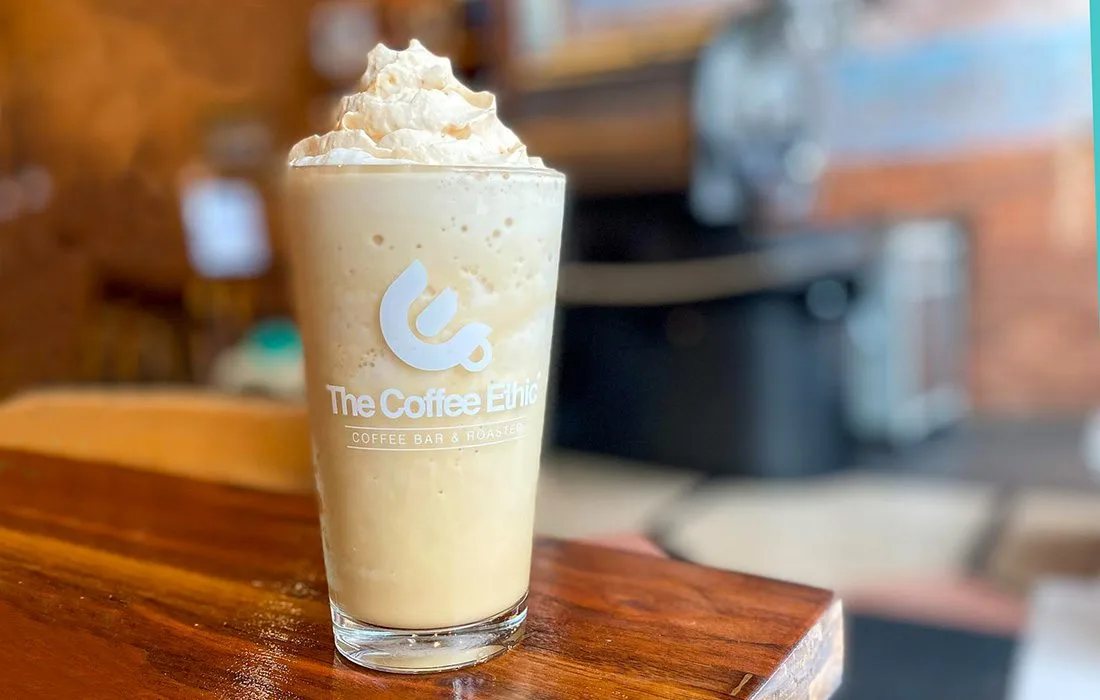 iced coffee beverage topped with whipped cream at café counter., the coffee ethic, missouri