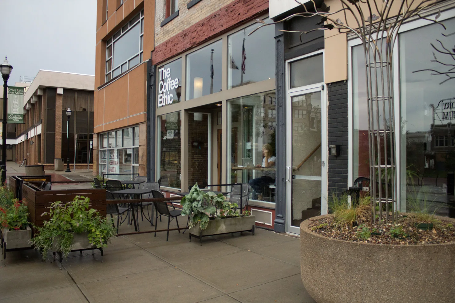 urban coffee shop storefront with outdoor seating and decorative planters., the coffee ethic, missouri