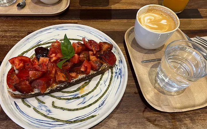 bruschetta with tomatoes and basil on decorative plate, latte with latte art, glass of water., the fix - café de especialidad