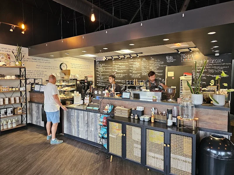 modern café interior with customer at counter, baristas working, menu boards visible., the muse coffee company & roastery, ra