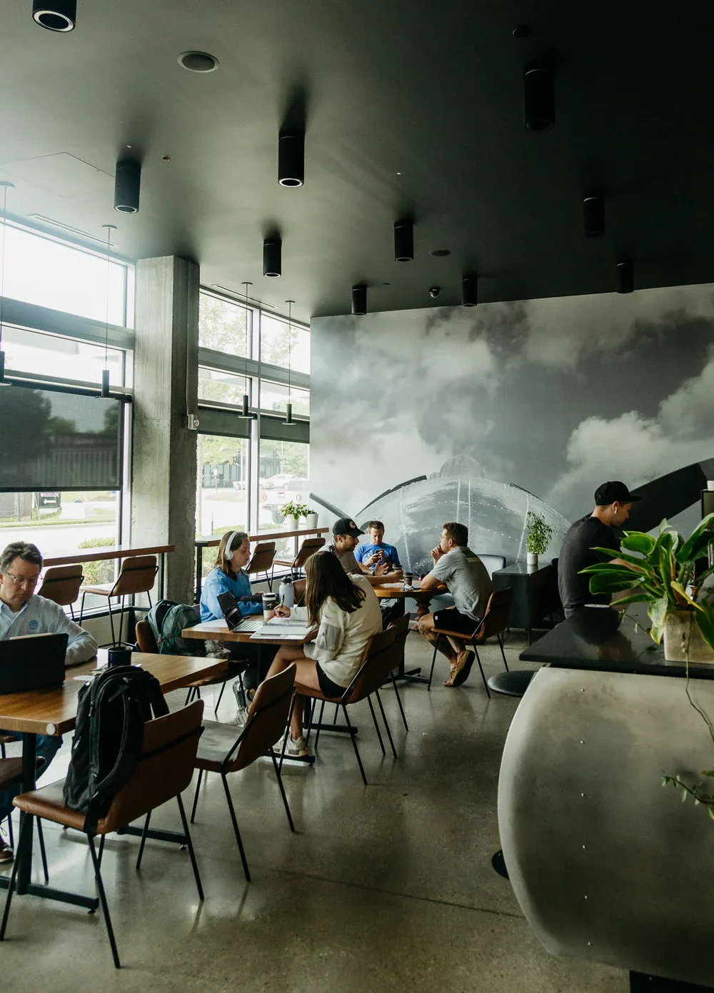 modern cafe with volcano mural, concrete floors, and seated patrons working., the roasterie factory cafe, kansas city