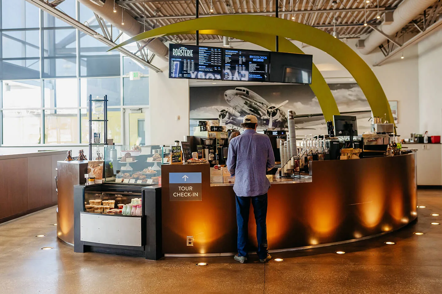 modern airport café with vintage airplane imagery and curved yellow architectural canopy., the roasterie factory cafe, kansas