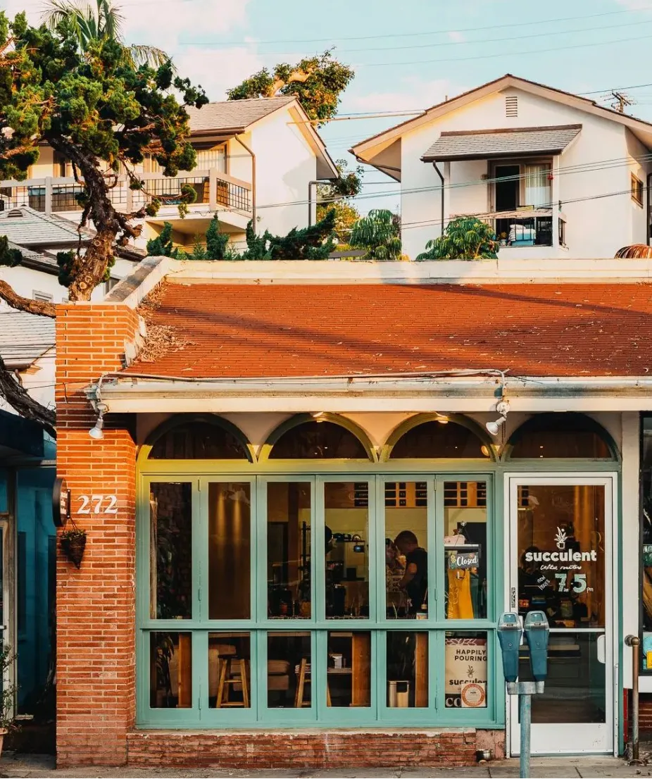 charming storefront with mint-green doors, brick facade, residential buildings behind., thorne brothers, laguna beach