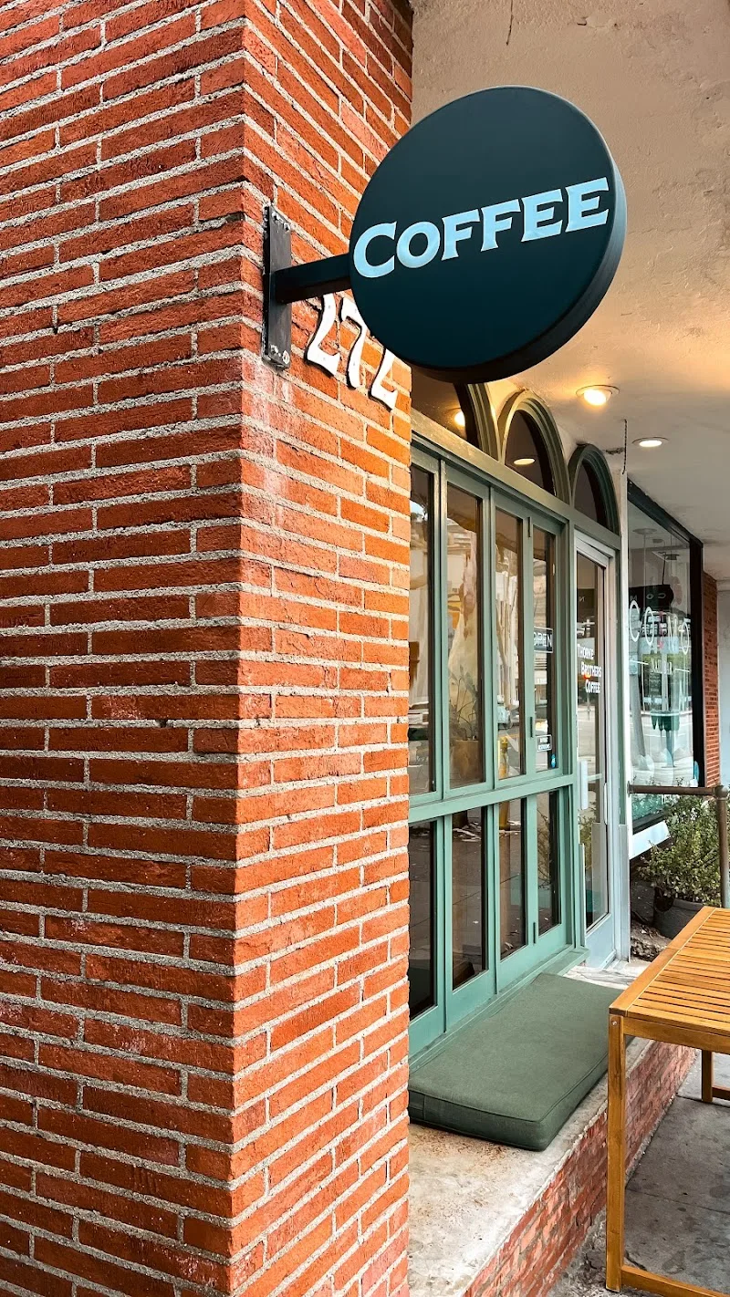 dark teal circular coffee shop sign mounted on red brick building exterior., thorne brothers, laguna beach