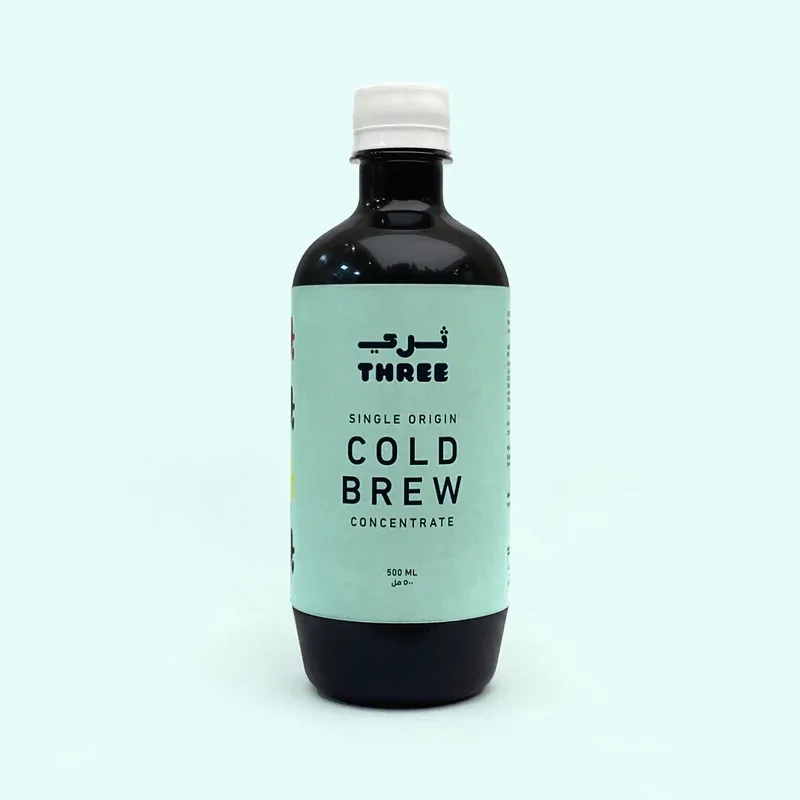black glass bottle with mint green label displaying "three single origin cold brew concentrate 500ml"., three coffee, dubai