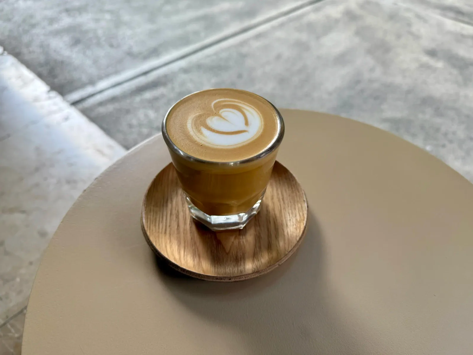 latte with heart latte art on wooden coaster at marble table., totte para todos, miguel hidalgo, mexico city