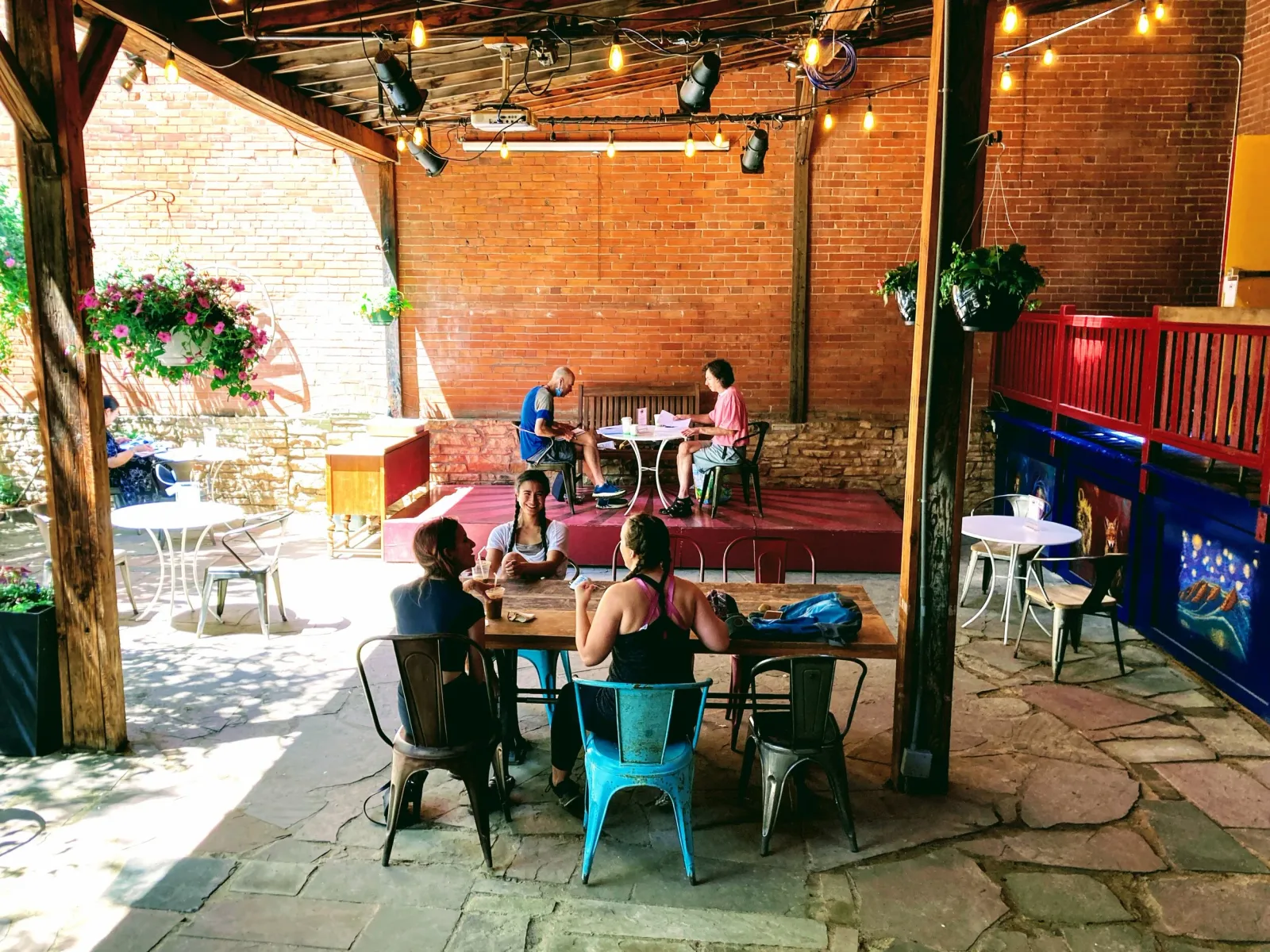 outdoor brick patio venue with people dining and socializing under string lights., trident booksellers and cafe, boulder