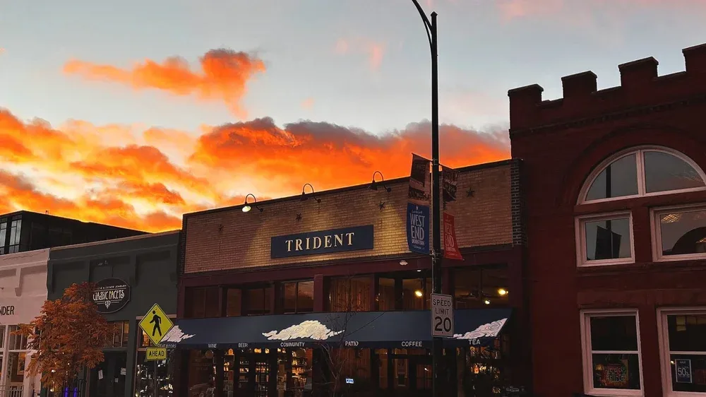 trident café storefront at sunset with dramatic orange sky and brick buildings., trident booksellers and cafe, boulder