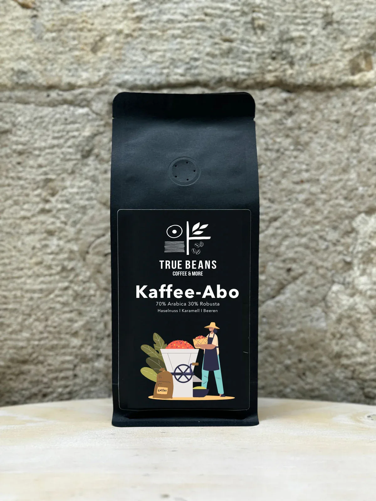 black coffee bag labeled "kaffee-abo" against textured brick wall background., truebeans specialty coffee - werksverkauf & se
