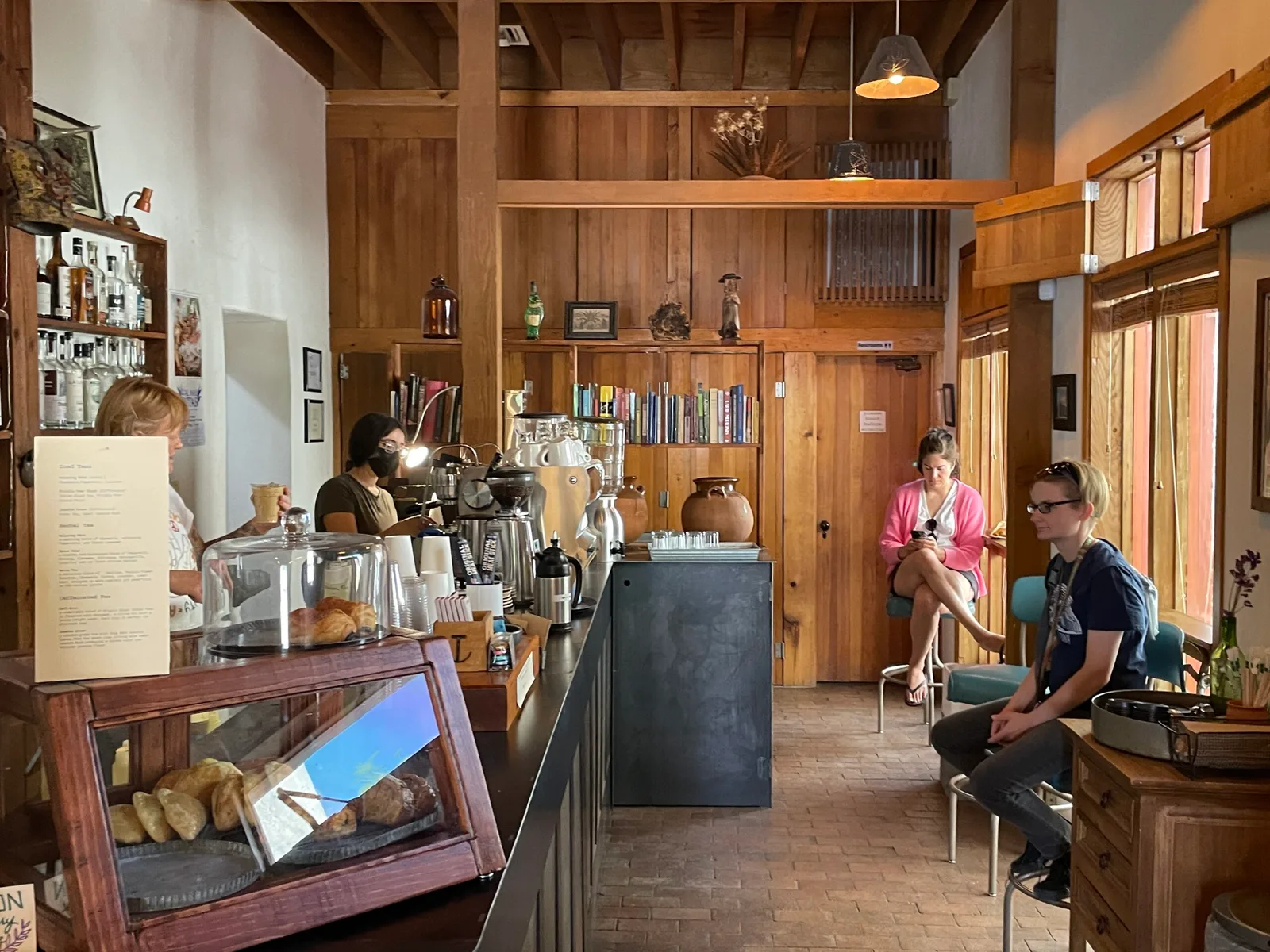 warm wooden café interior with customers, espresso machine, and pastry display case., tucson coffee roasters, arizona